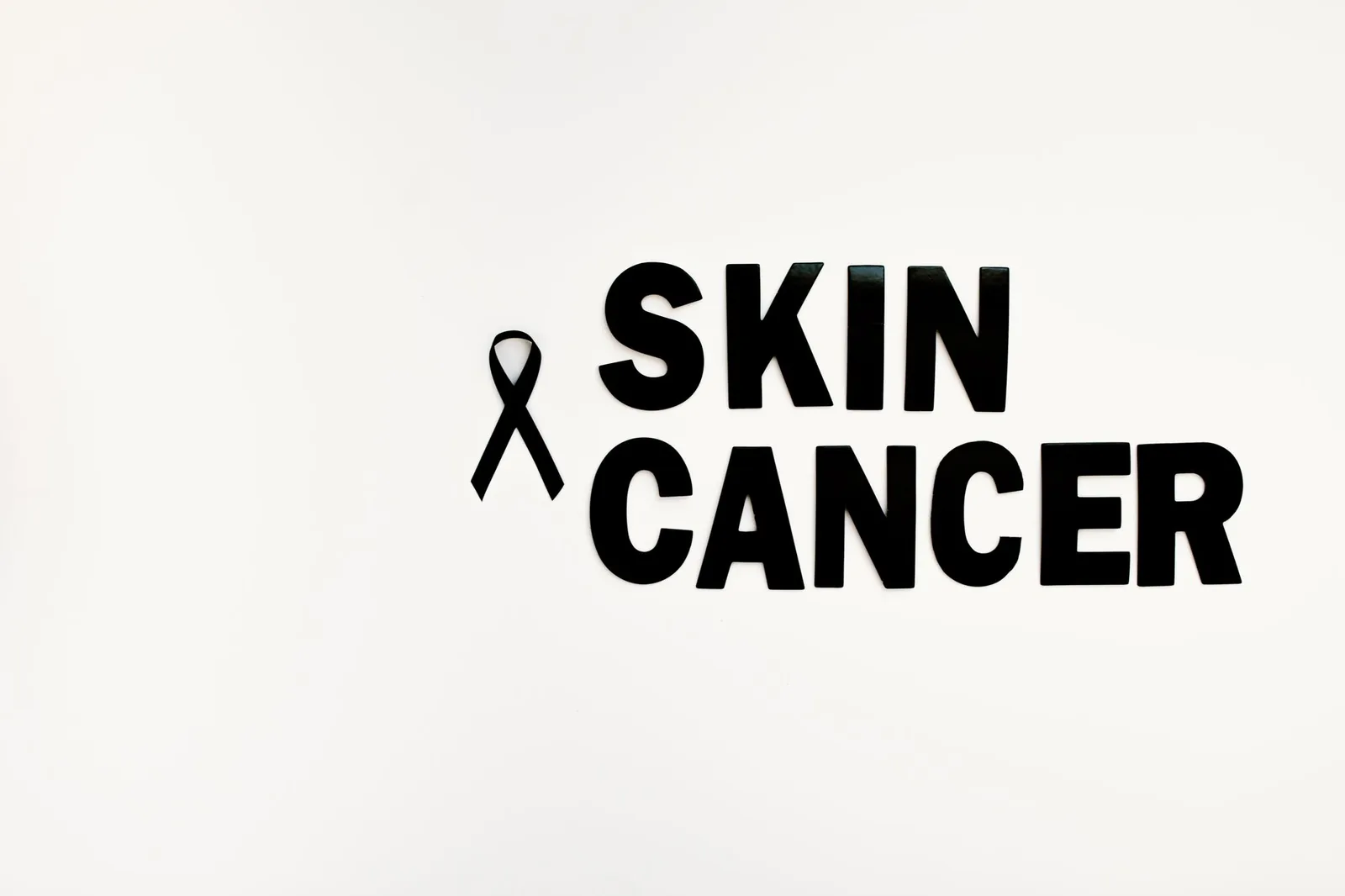 Black ribbon and text highlighting skin cancer awareness on a white background.