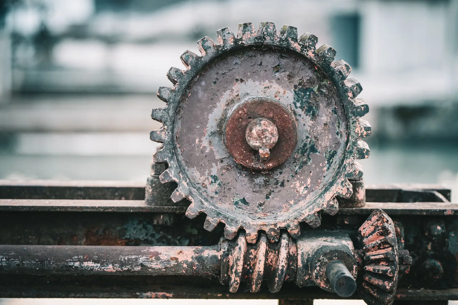 Close-up of a rustic industrial gear with peeling paint, highlighting its aged texture.