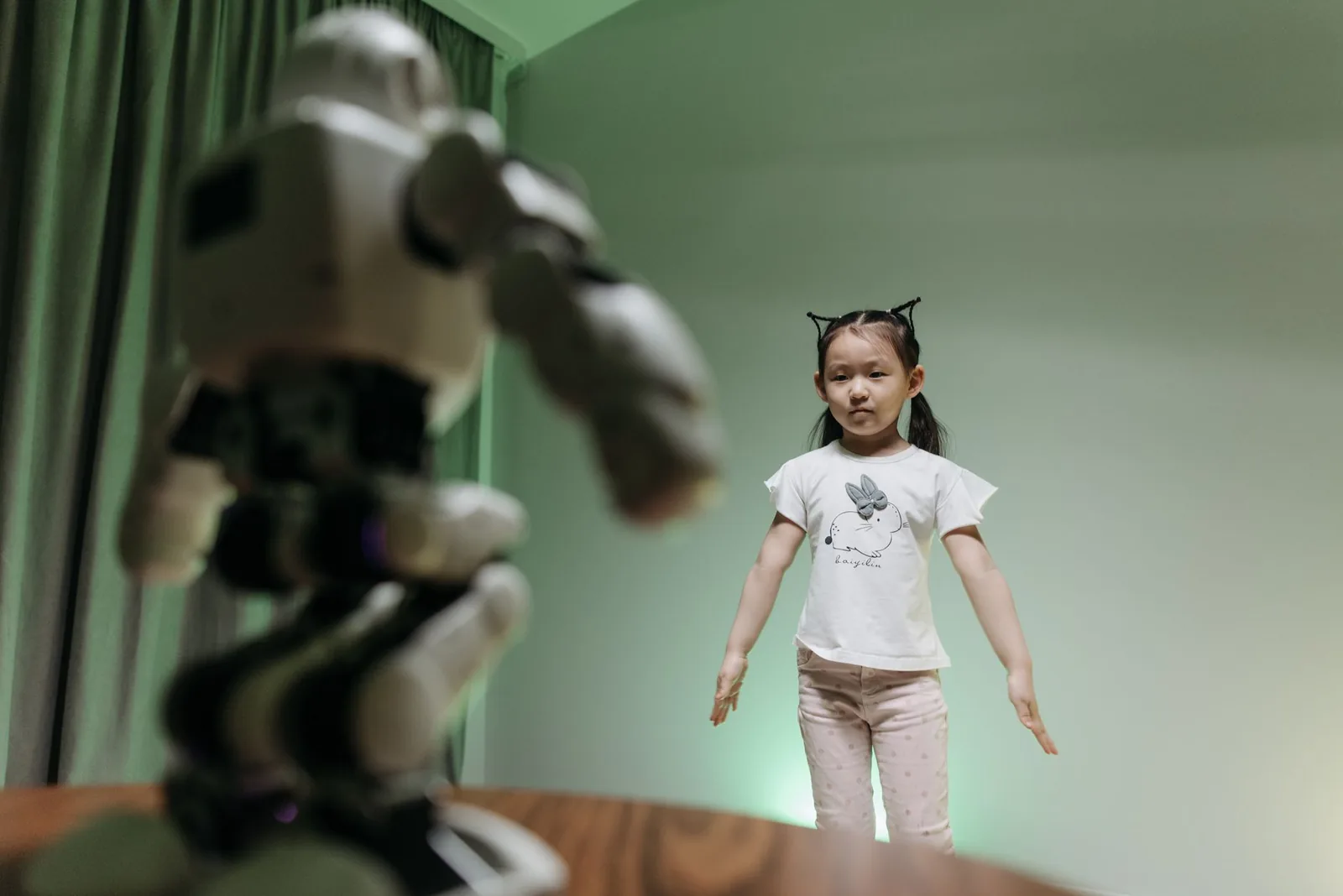 An Asian child interacts with a humanoid robot indoors, embracing innovation and play.