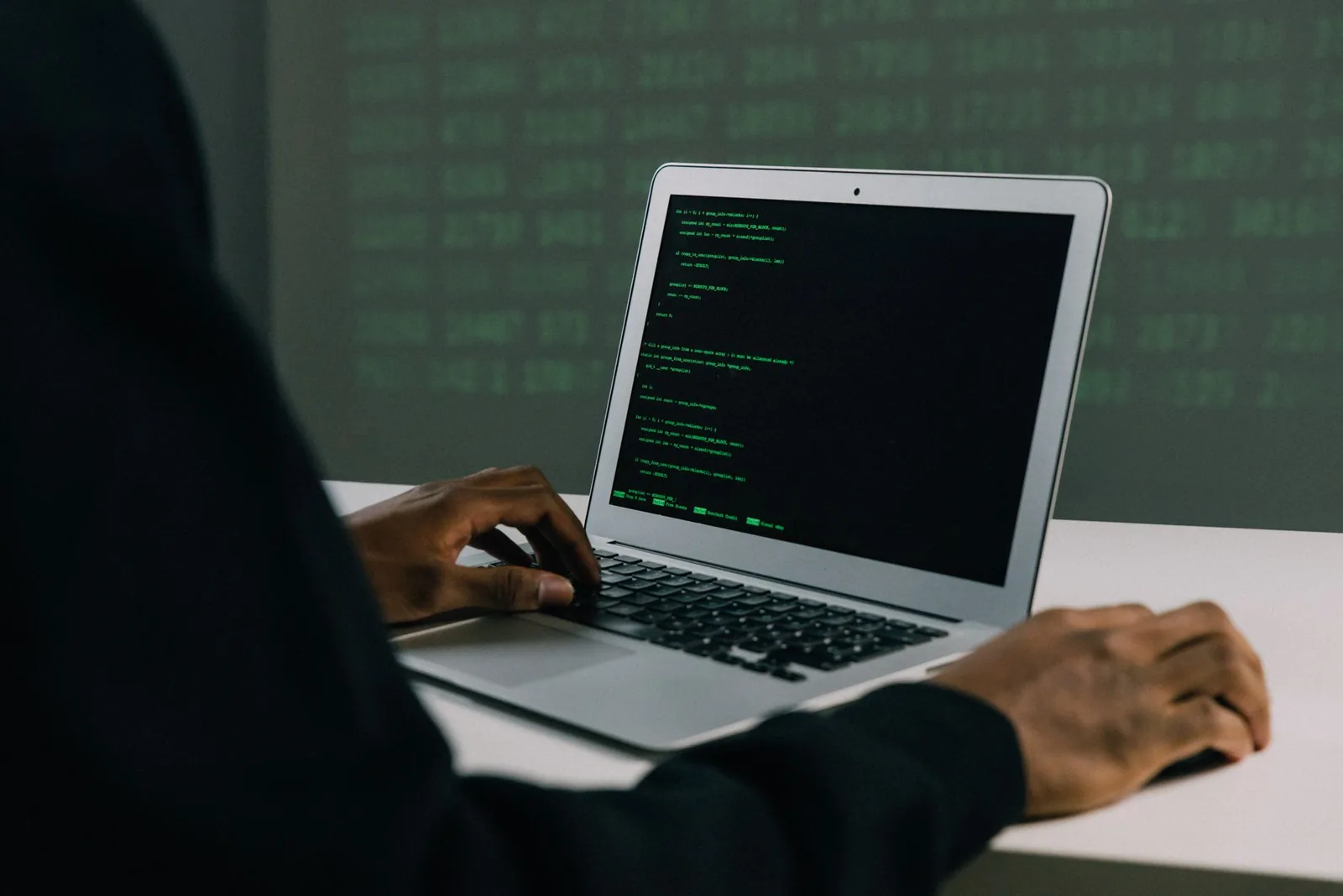 A focused adult working on a laptop demonstrates modern cybersecurity and coding skills indoors.