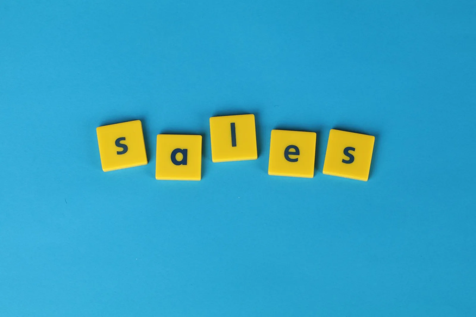 Yellow Scrabble tiles spelling 'sales' on a vibrant blue background. Perfect for marketing and business themes.
