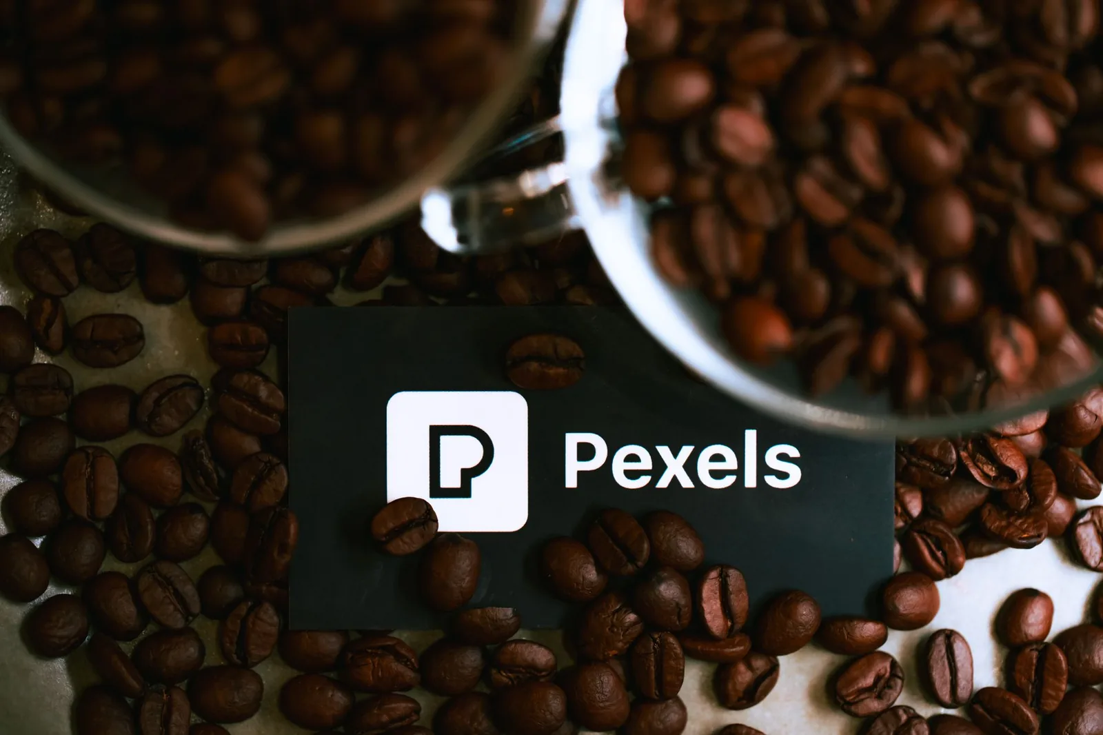 Top view of coffee beans spilling around a branding card, perfect for coffee-related promotions.