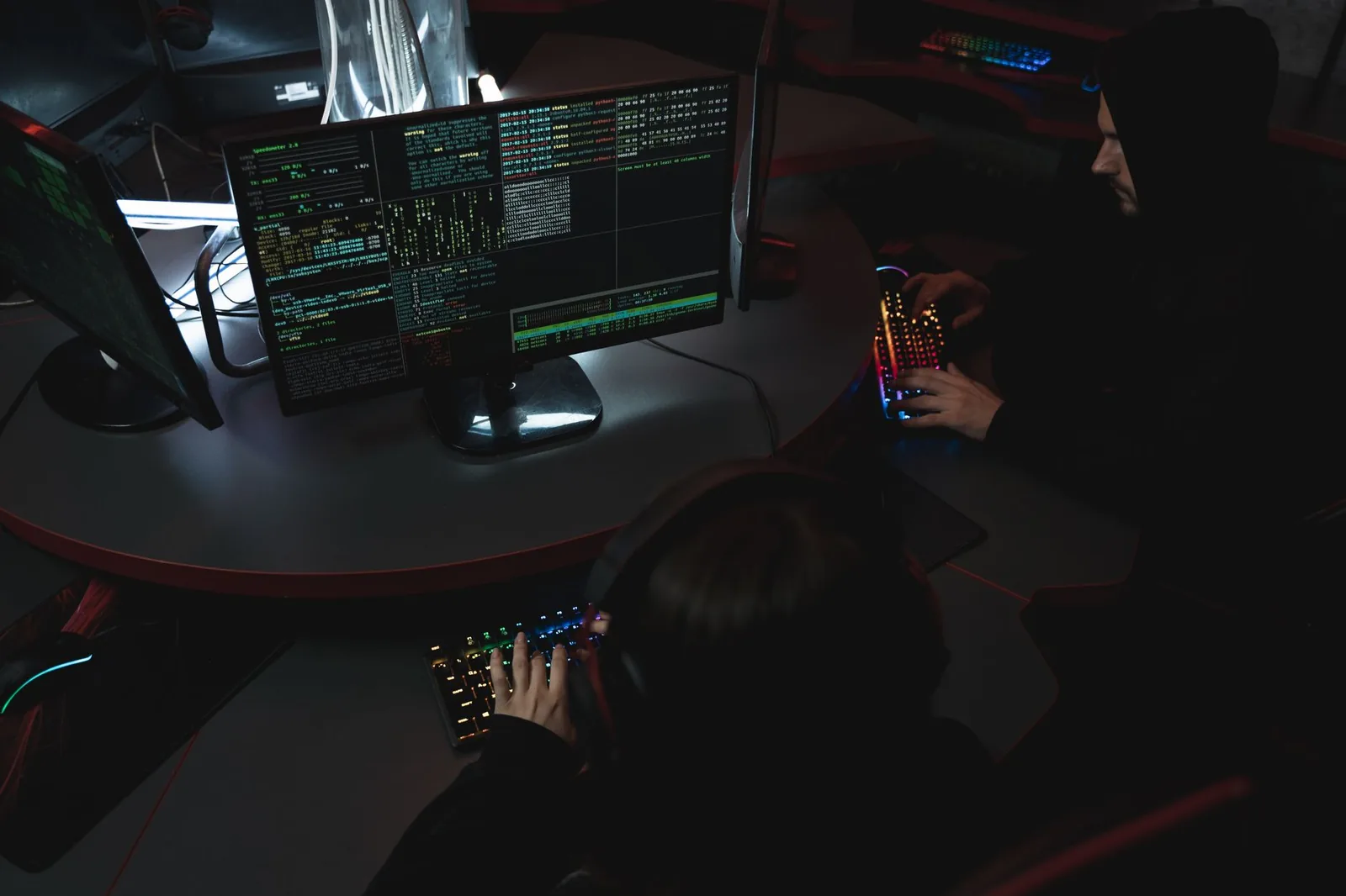 A group of people in a dark room working on computers, related to cybersecurity.
