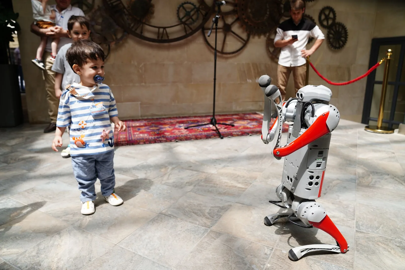 A young boy engages with a humanoid robot during an indoor tech exhibition, symbolizing future innovation.